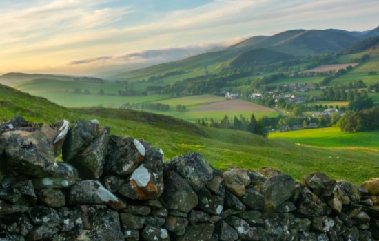 Countryside view with stone wall in the front and rolling hills behind. Countryside view with stone wall in the front and rolling hills behind.