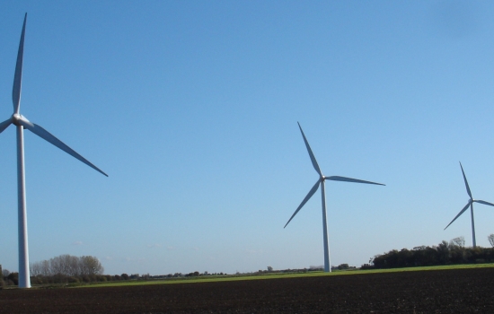 Four wind turbines in a field with blue sky