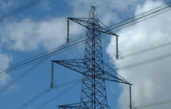Electricity pylon outside with a blue sky and white clouds behind Electricity pylon outside with a blue sky and white clouds behind