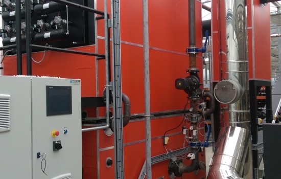 Large red biomass boiler with sliver pipes in a greenhouse Large red biomass boiler with sliver pipes in a greenhouse