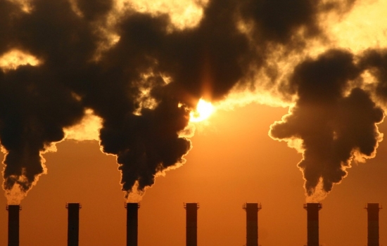 A factory with chimney smoking with a sunset behind A factory with chimney smoking with a sunset behind