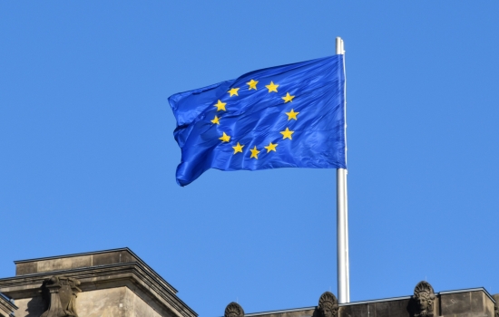 European flag flying above a building with a blue sky background European flag flying above a building with a blue sky background