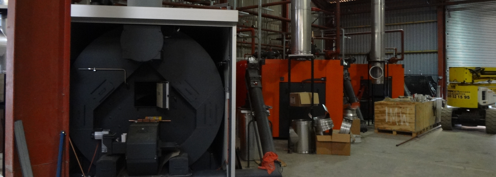 Three biomass boilers being installed in a shed