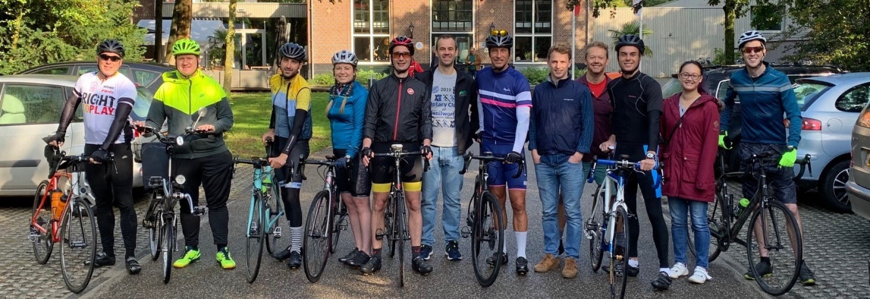 Group of cyclists with bikes and a brick building in the background