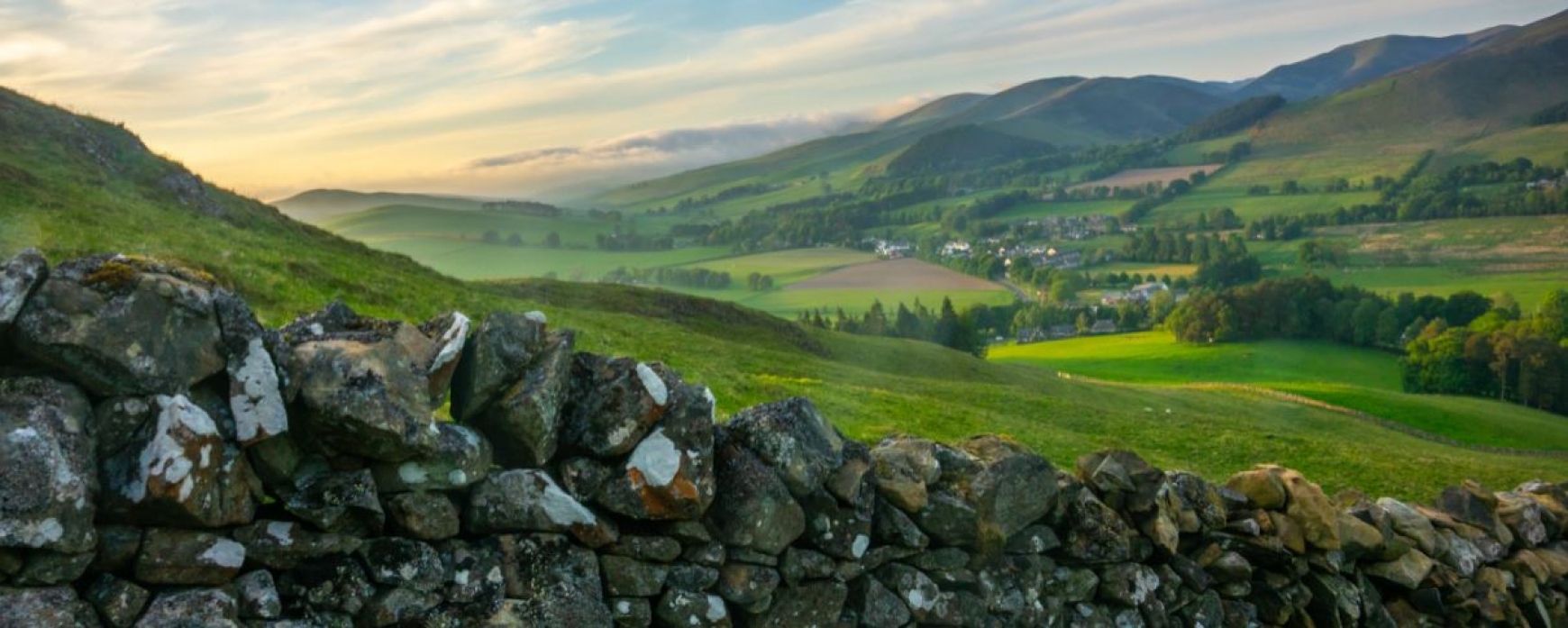 Countryside view with stone wall in the front and rolling hills behind. 