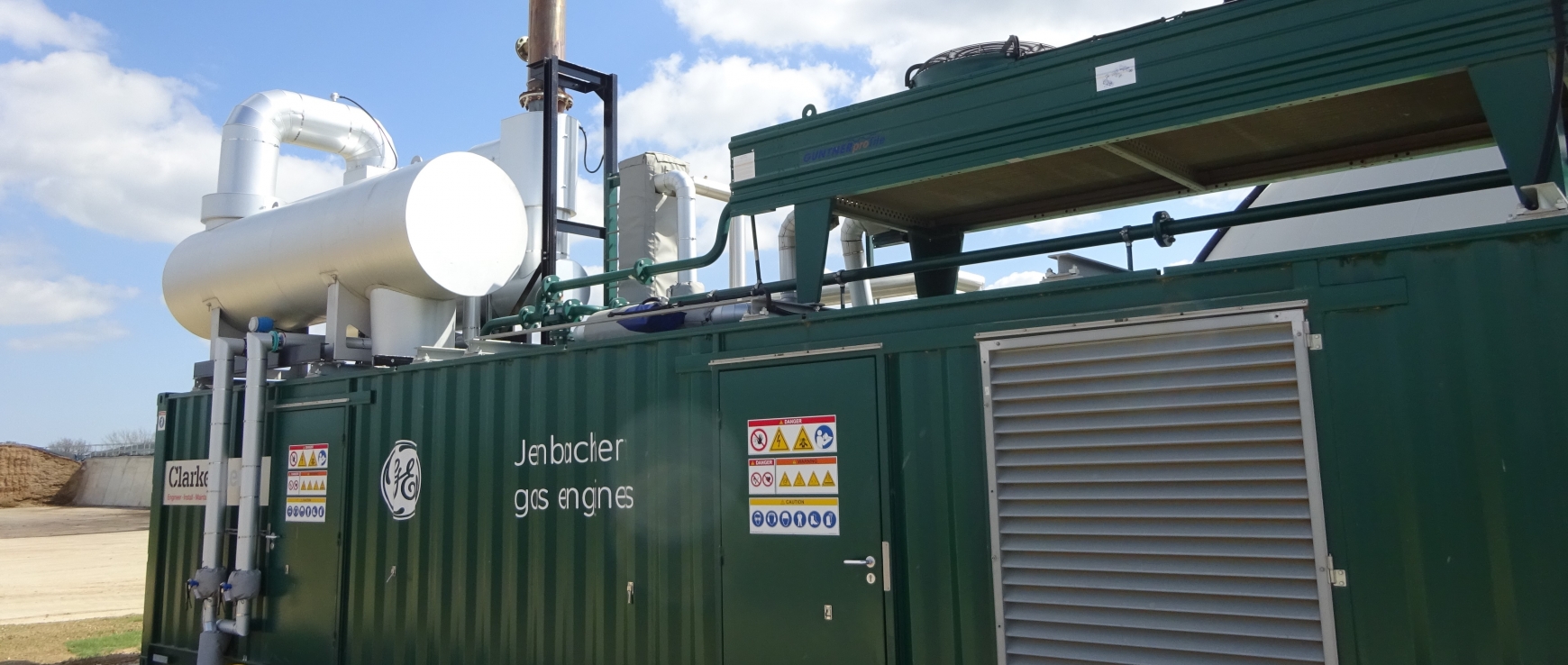 Green CHP engine with blue sky behind