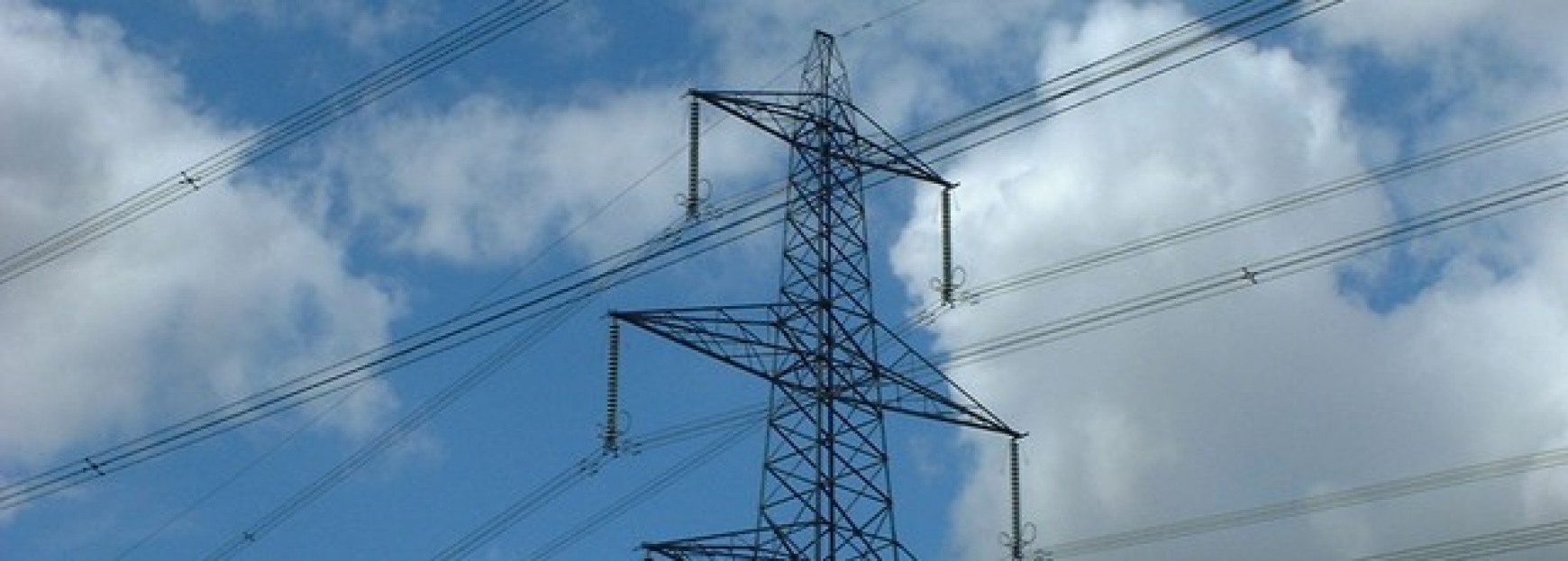 Electricity pylon outside with a blue sky and white clouds behind