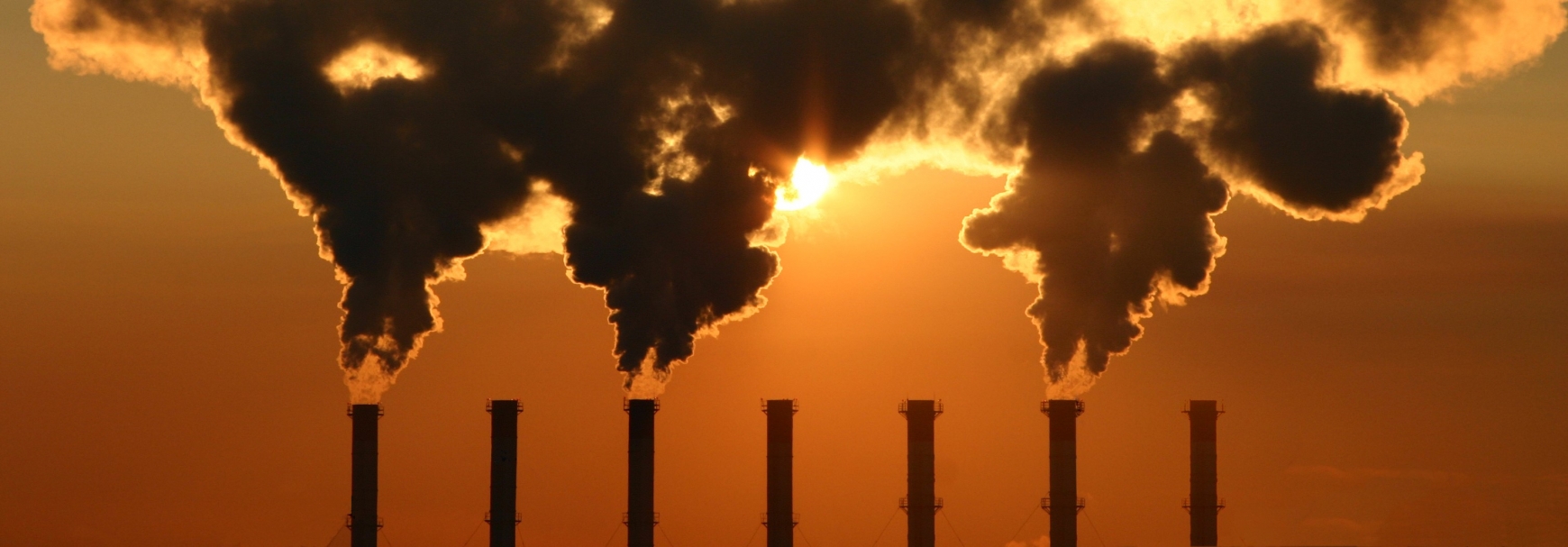 Chimney with smoke against a sunset