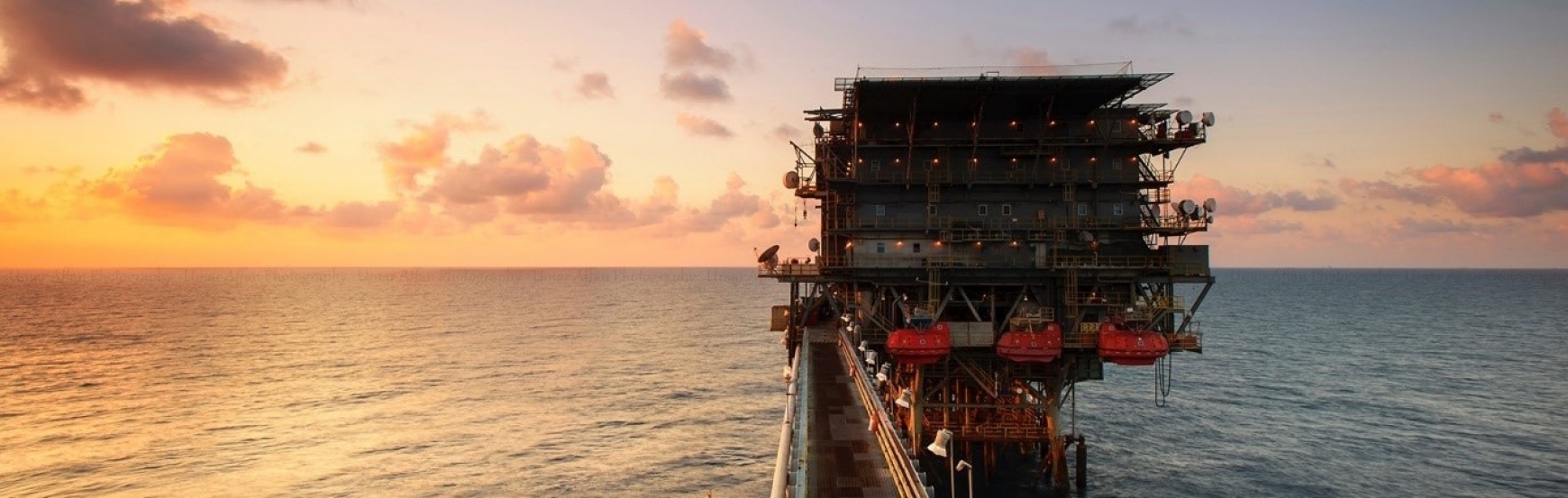 oil rig in the ocean with a sunset