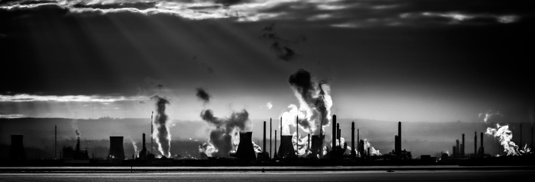 A black and white outline of a factory with smoke