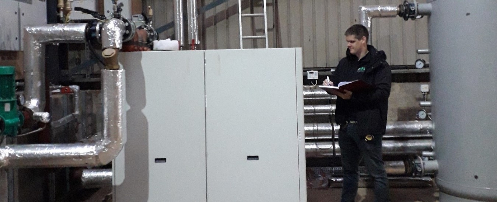 Person looking at machinery in a shed with pipework