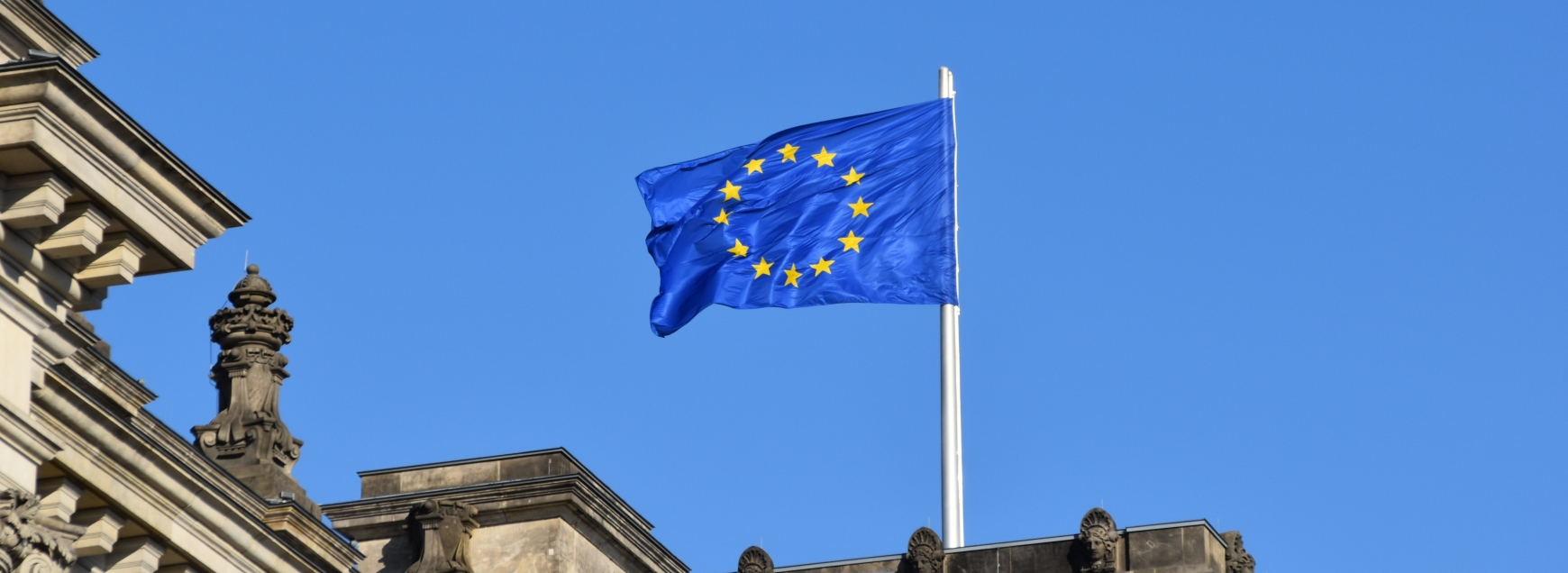 European flag flying above a building with a blue sky background
